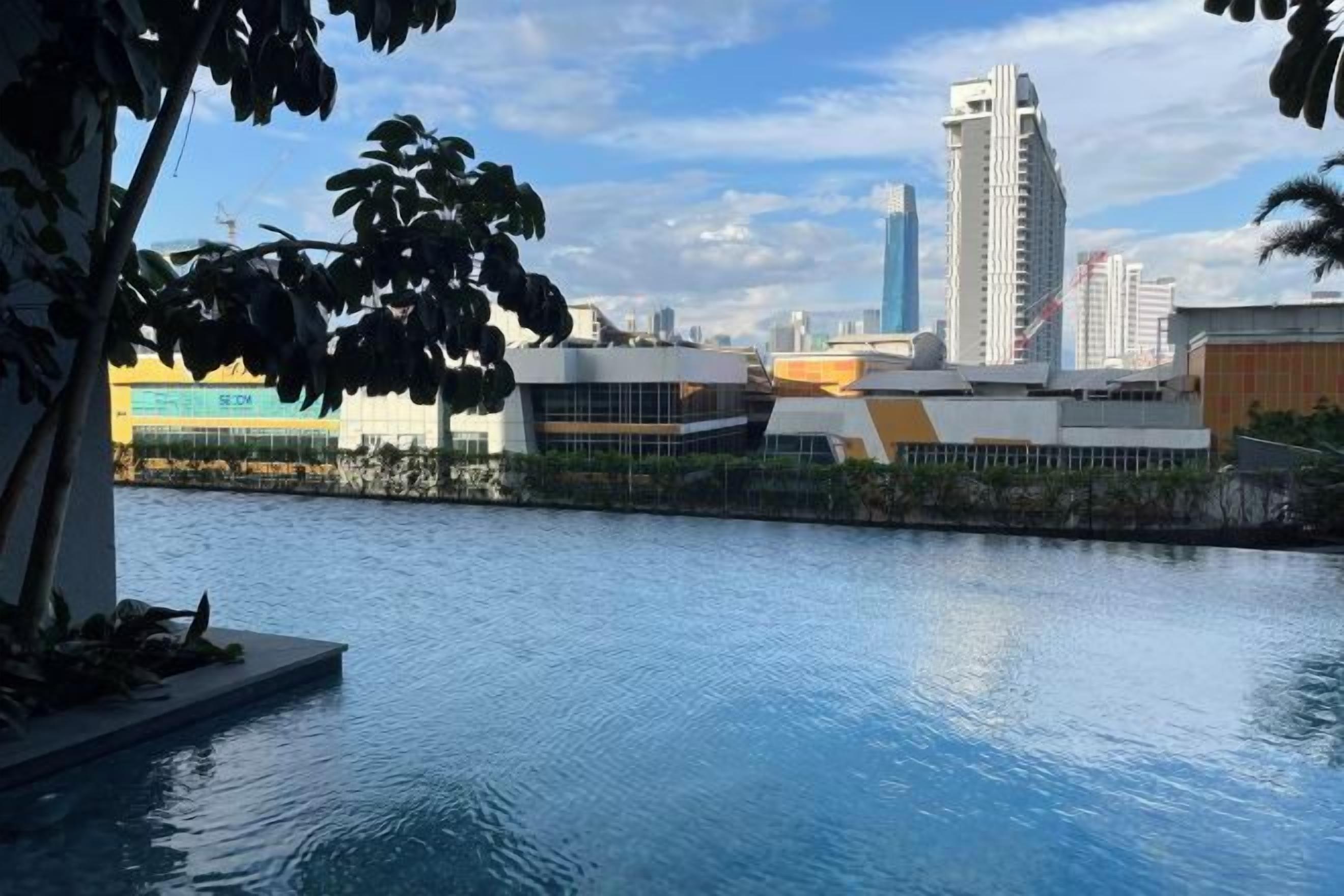 A pool area with a view of modern buildings and a clear sky.