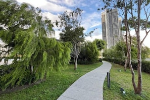 A pathway in a landscaped area with trees and a tall building in the background. - Residence Trion 1 by Awesomestay (Kuala Lumpur)
