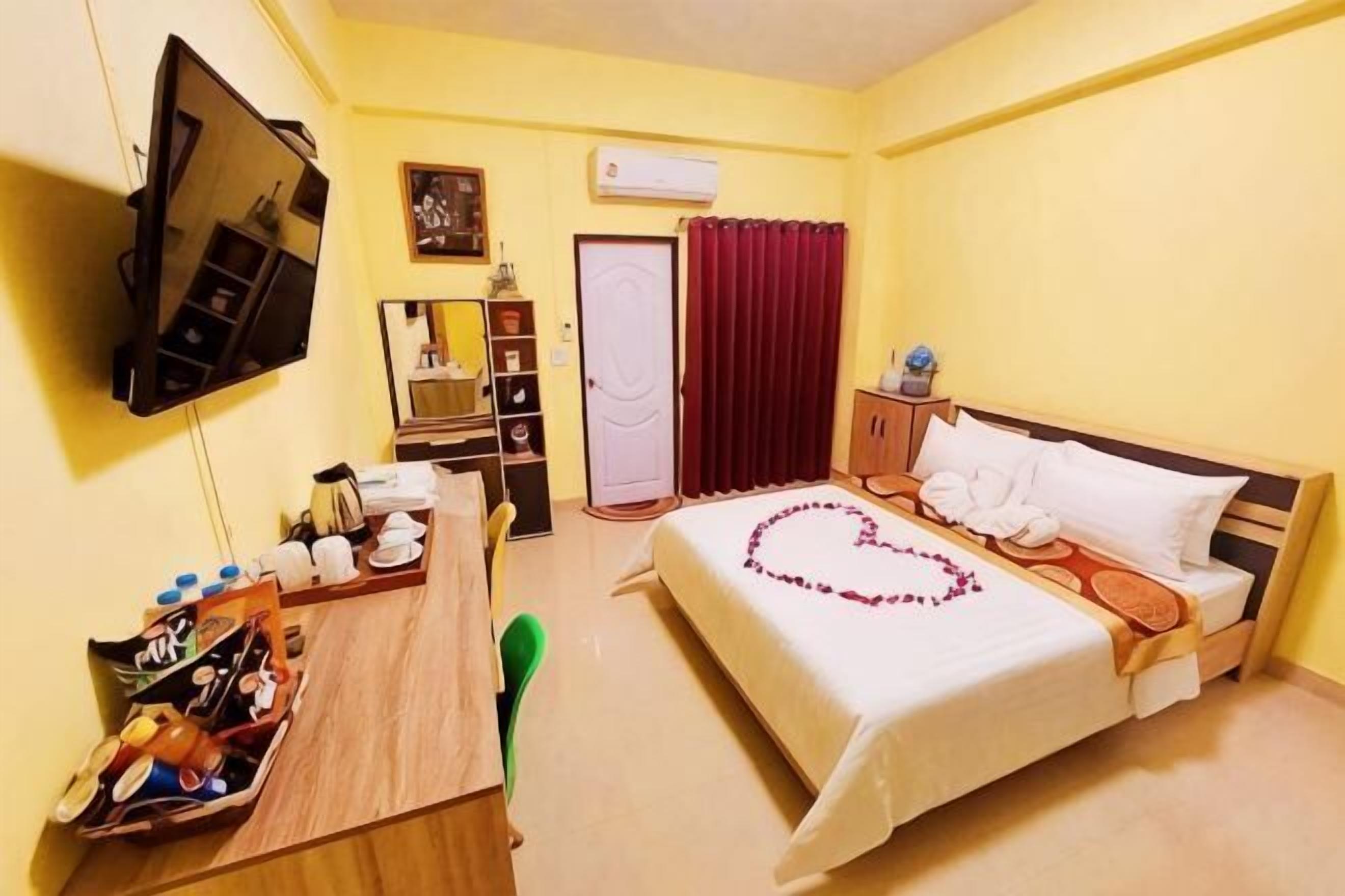 A hotel room with a bed, a desk, a chair, a TV, a wardrobe, and a door.