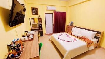 A hotel room with a bed, a desk, a chair, a TV, a wardrobe, and a door.