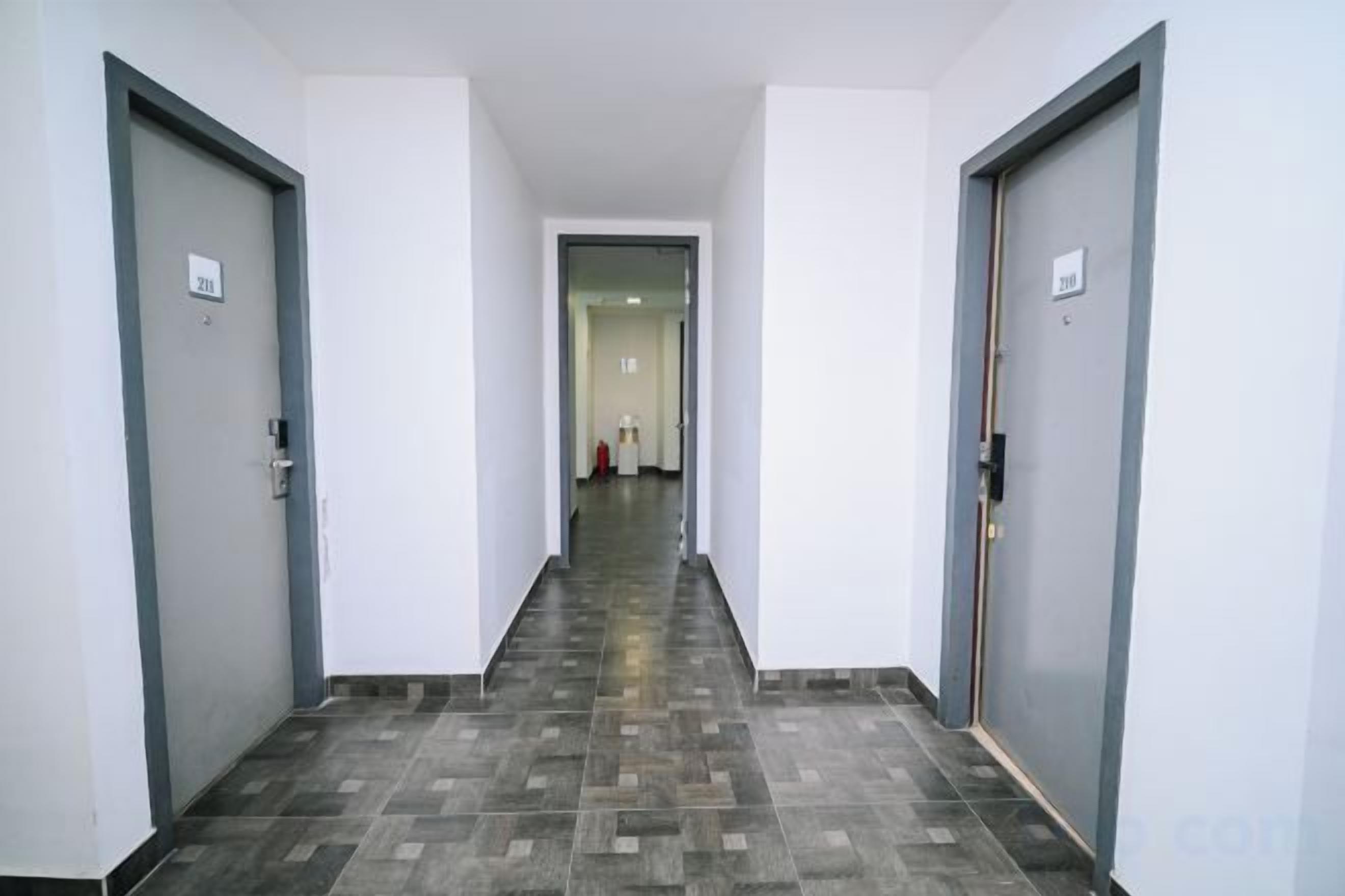 A hallway with two doors on either side, a tiled floor, and a light-colored wall.