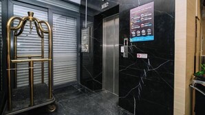 A hotel lobby with a closed elevator door, a wall-mounted sign, and a golden luggage cart. - Kingston Hotel 2 @ Setapak (Kuala Lumpur)