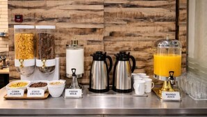 A breakfast bar with labeled containers of corn flakes, coco crunch, and fresh milk, along with coffee makers and a juice dispenser. - Kingston Hotel 2 @ Setapak (Kuala Lumpur)