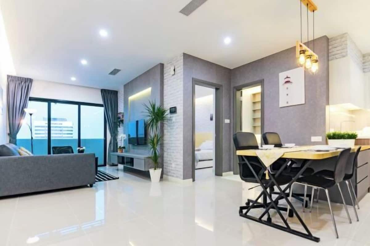 A modern hotel room with a dining area, a sofa, a potted plant, and a view of the city.