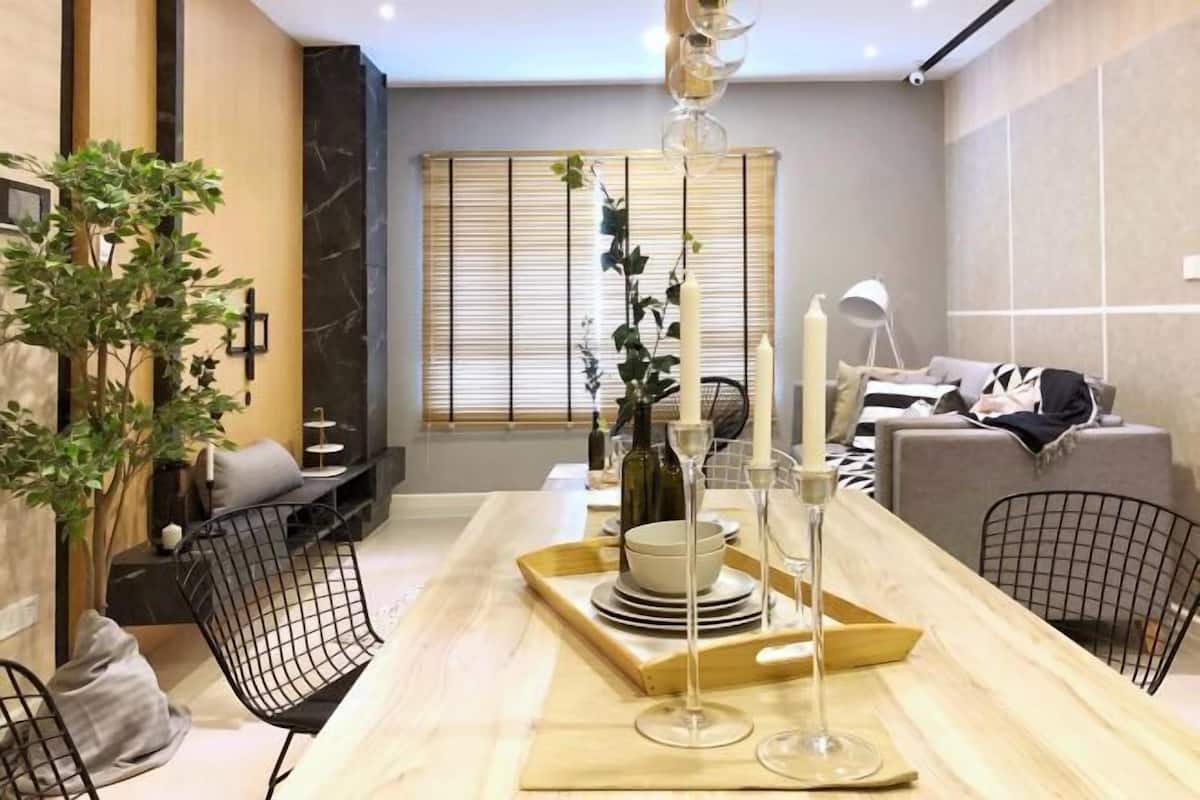 A modern living room with a wooden dining table set for a meal, a sofa, and a potted plant.