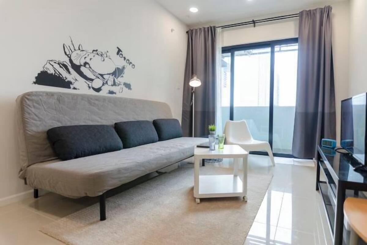 A modern living room with a grey sofa, a white coffee table, and a flat-screen TV.