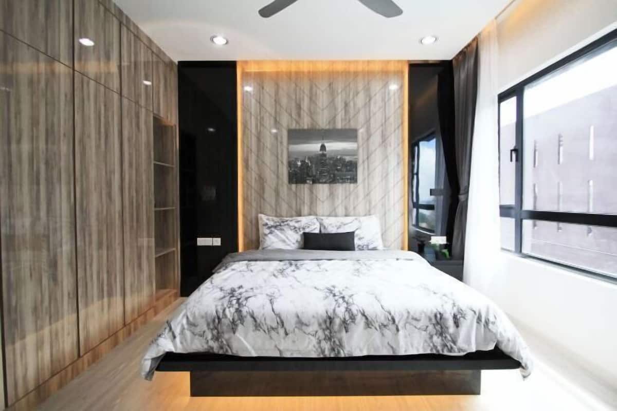 A modern bedroom with a bed, a cityscape picture on the wall, and a window with a view.