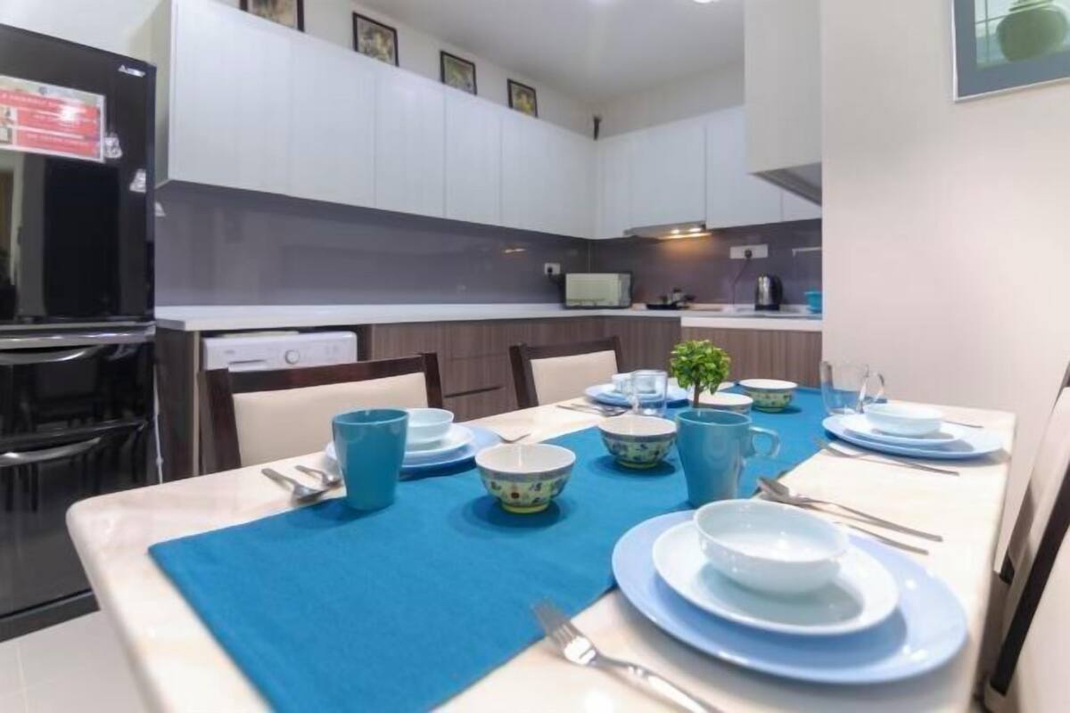 A modern kitchen with white cabinets, a microwave, and a dining area with blue tableware.