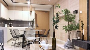 Una cocina moderna con armarios blancos, una zona de comedor con sillas de metal y una mesa central con un jarrón y tetera.