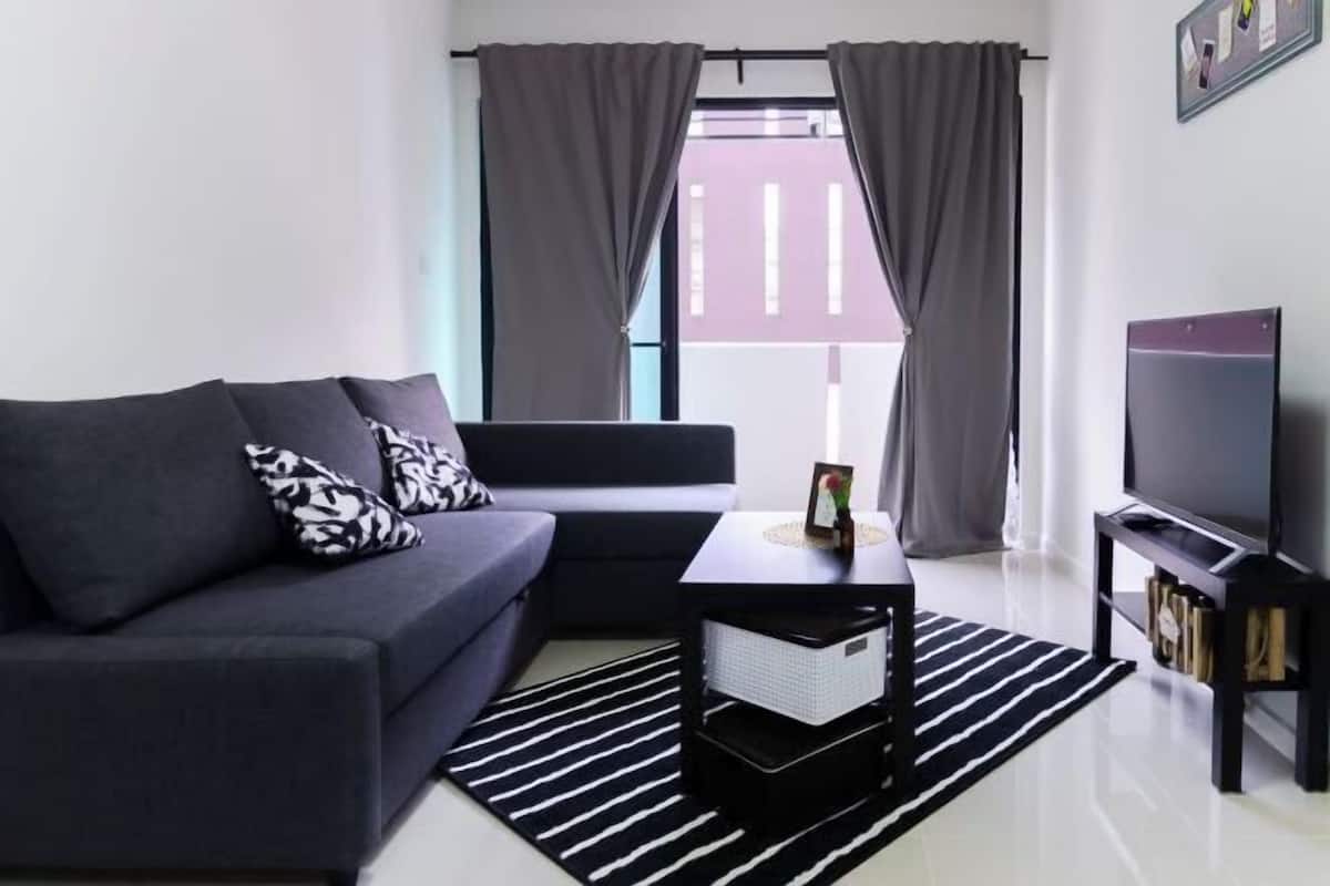 A modern living room with a sofa, a coffee table, a TV, and a window with curtains.