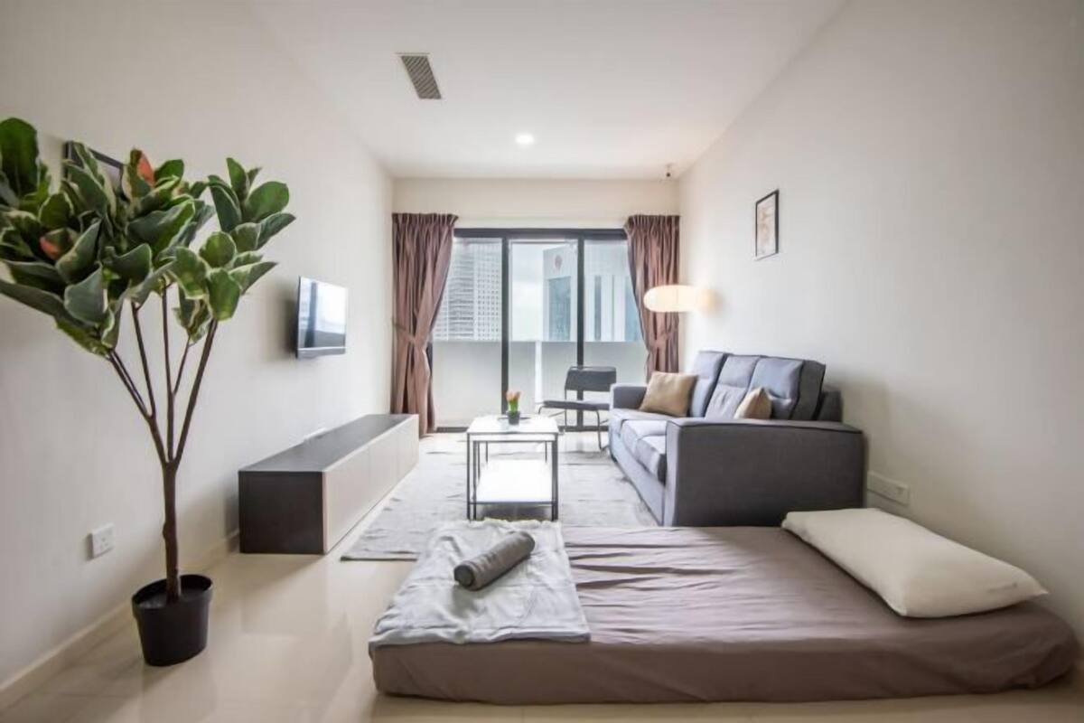 A modern living room with a sofa, a coffee table, a TV, and a large window with curtains.