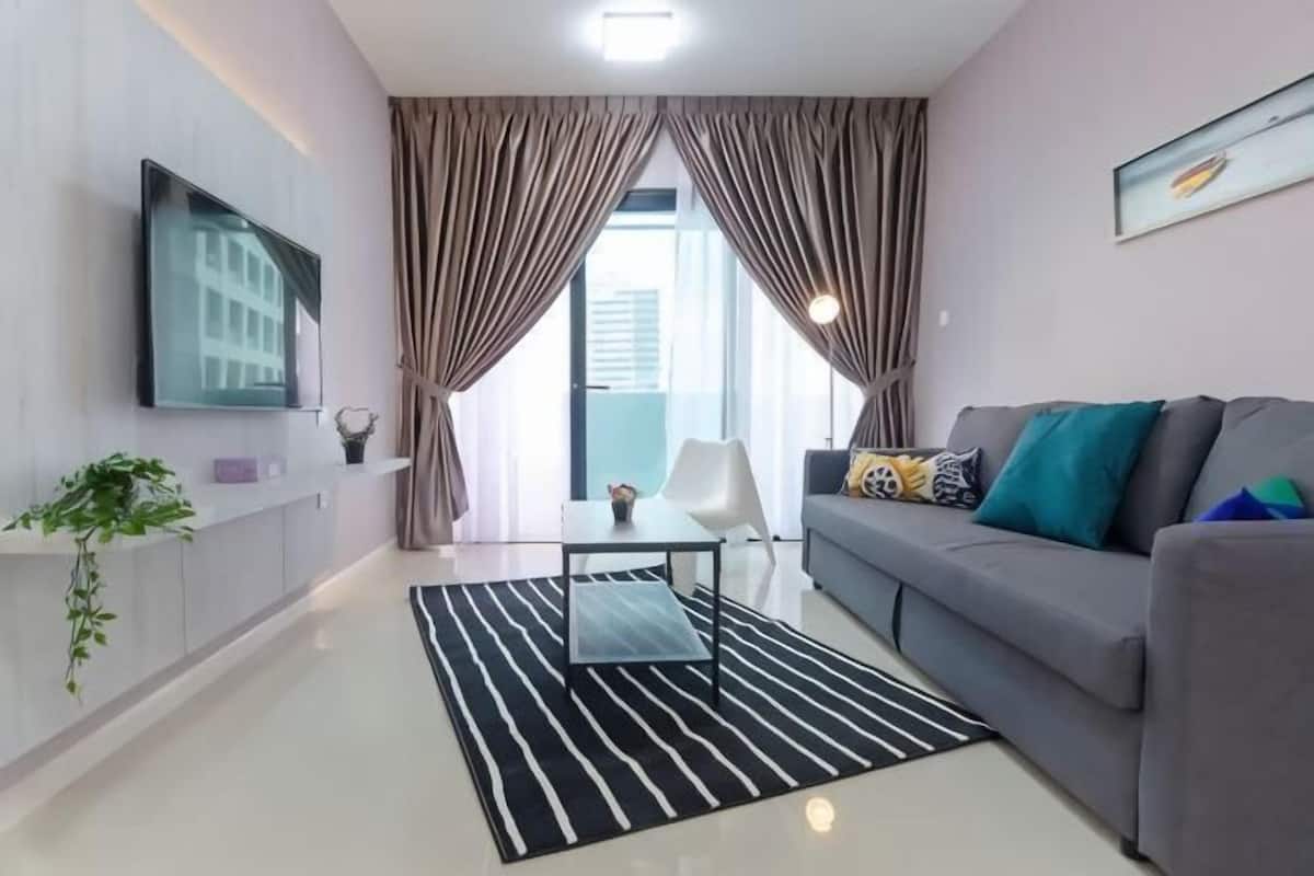 A modern living room with a sofa, a coffee table, and a TV mounted on the wall.