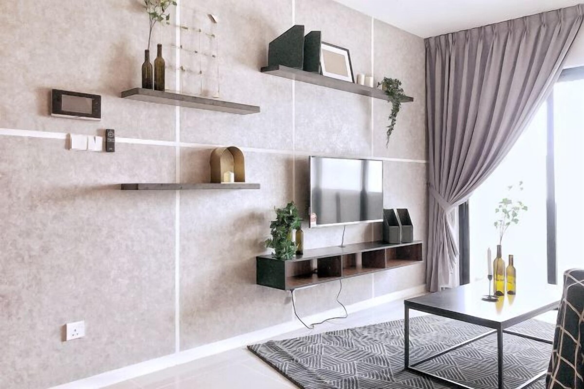 Una sala de estar moderna con un televisor de pantalla plana, estanterías empotradas y un tapete estampado.