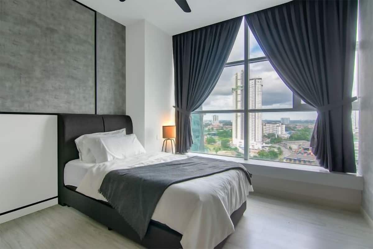 A modern bedroom with a large bed, a view of the cityscape through a window, and a minimalist design.