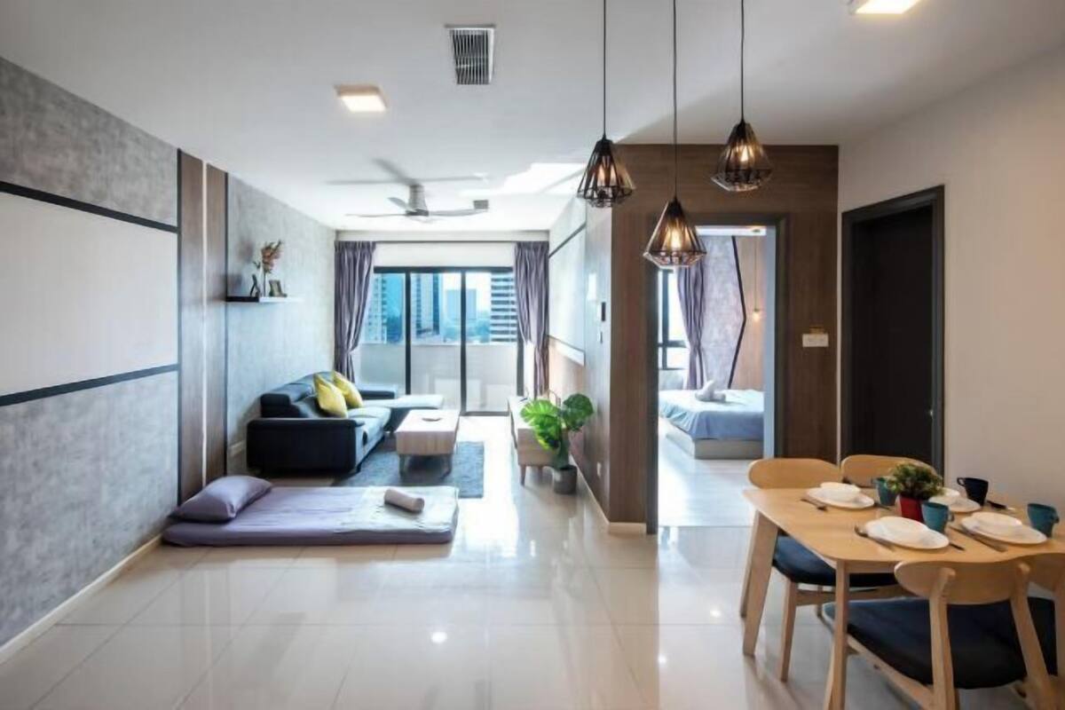 A modern living room with a sofa, a dining table set for two, and a large window with curtains.