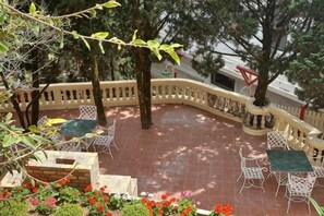 A patio with outdoor seating, surrounded by a curved railing, and trees providing shade. - Thi Tran Co Da Lat (Dalat)