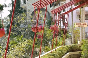 A hotel with red structural elements, a sign reading 'THI TRÃN CÒ,' and lush greenery in the background. - Thi Tran Co Da Lat (Dalat)