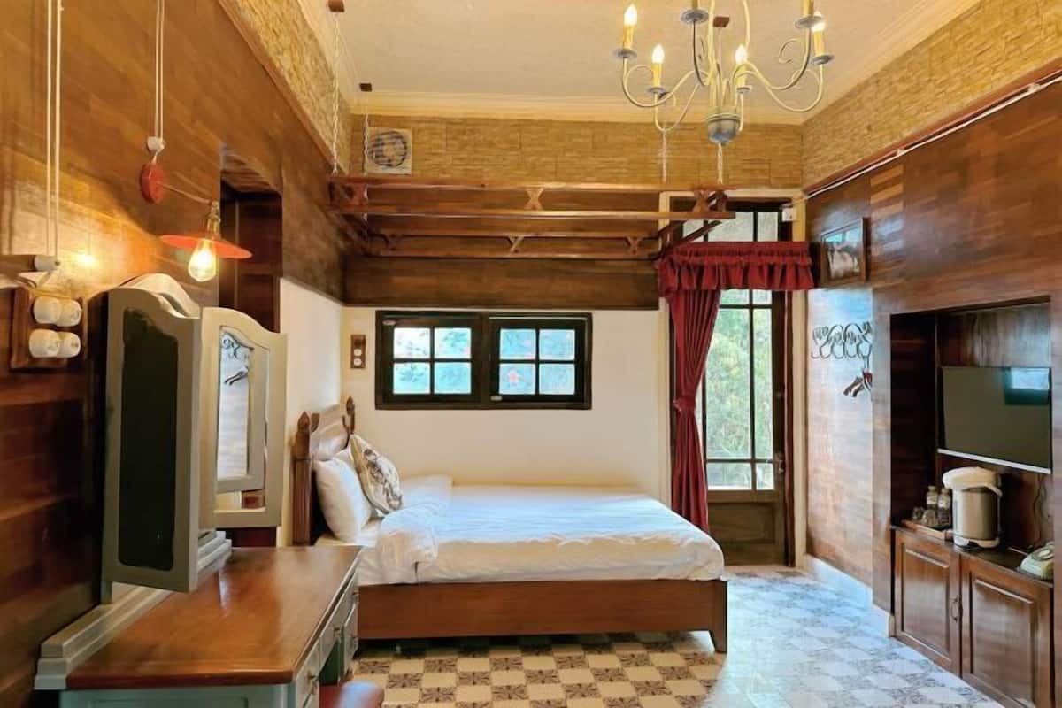 Une chambre à coucher avec un lit en bois, un bureau, une télévision et un lustre.