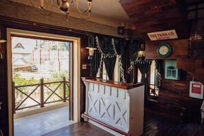 A wooden interior with a reception desk, a clock, and a sign that reads 'TRIANÓ CO'. - Thi Tran Co Da Lat (Dalat)