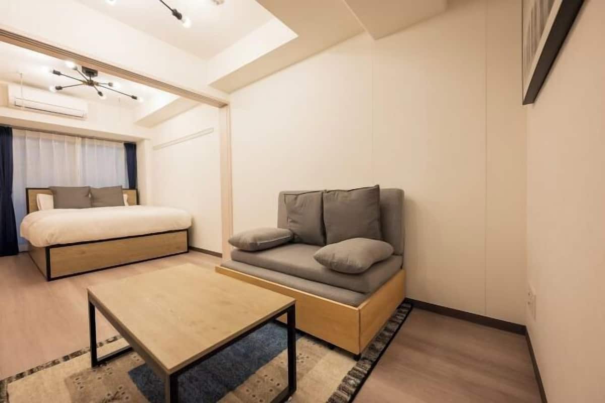 A compact, modern room with a bed, sofa, and a small table.