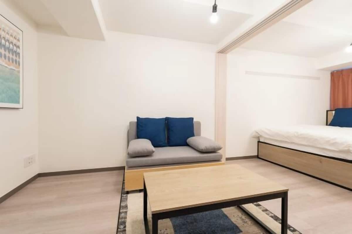 A bedroom with a bed, a sofa, a coffee table, and a painting on the wall.