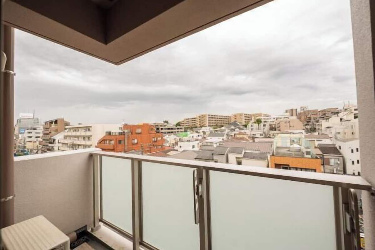 A balcony with a view of a cityscape, including various buildings and a cloudy sky.