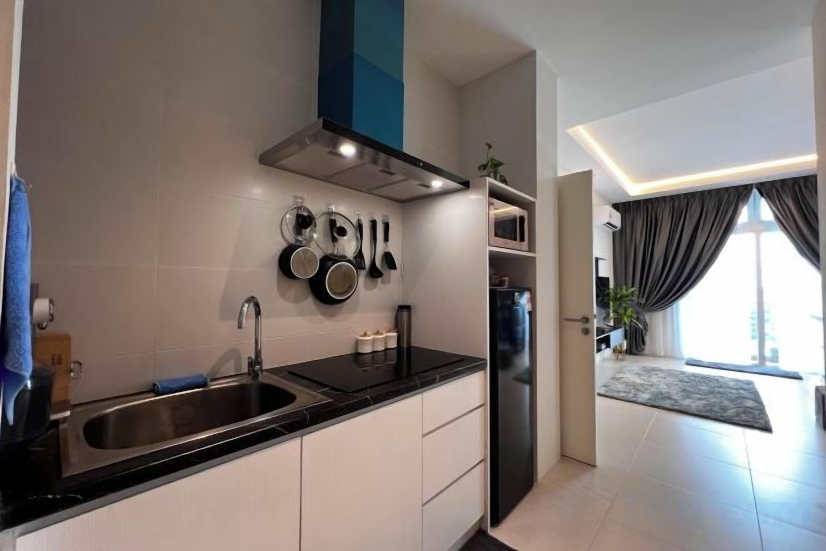 A modern kitchen with a black countertop, stainless steel sink, and a range hood.