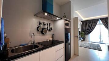 A modern kitchen with a black countertop, stainless steel sink, and a range hood.