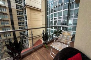 A balcony with a metal railing, potted plants, and a white chair. - LoFF Suite River View 2 Bedroom at Riverine Diamond Resort (Kuching)