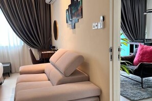 Un salon moderne avec un canapé, un coin repas avec une table et une vue sur l’extérieur.