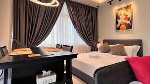 Een moderne hotelkamer met een bed, een eettafel met stoelen, een kroonluchter en een schilderij aan de muur.