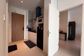 Una cocina compacta con microondas, un refrigerador negro y una pequeña mesa.