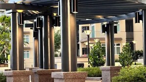 Een overdekt buitengebied met metalen pilaren en een pergola.