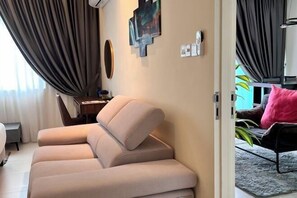 Una sala de estar moderna con un sofá color beige, una mesita auxiliar y un cuadro en la pared.