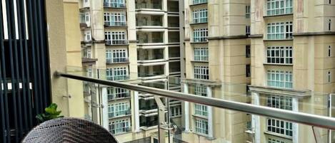 Un edificio de gran altura con múltiples balcones, un parque infantil debajo y una barandilla metálica en primer plano.