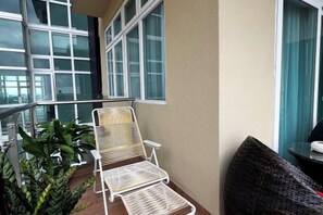Un balcon avec une chaise en métal blanc, une chaise en osier et un pot de fleurs.