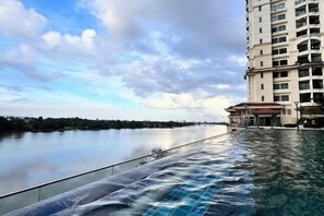 A hotel with a swimming pool, a view of a river, and a multi-story building. - LoFF Suite River View 2 Bedroom at Riverine Diamond Resort (Kuching)