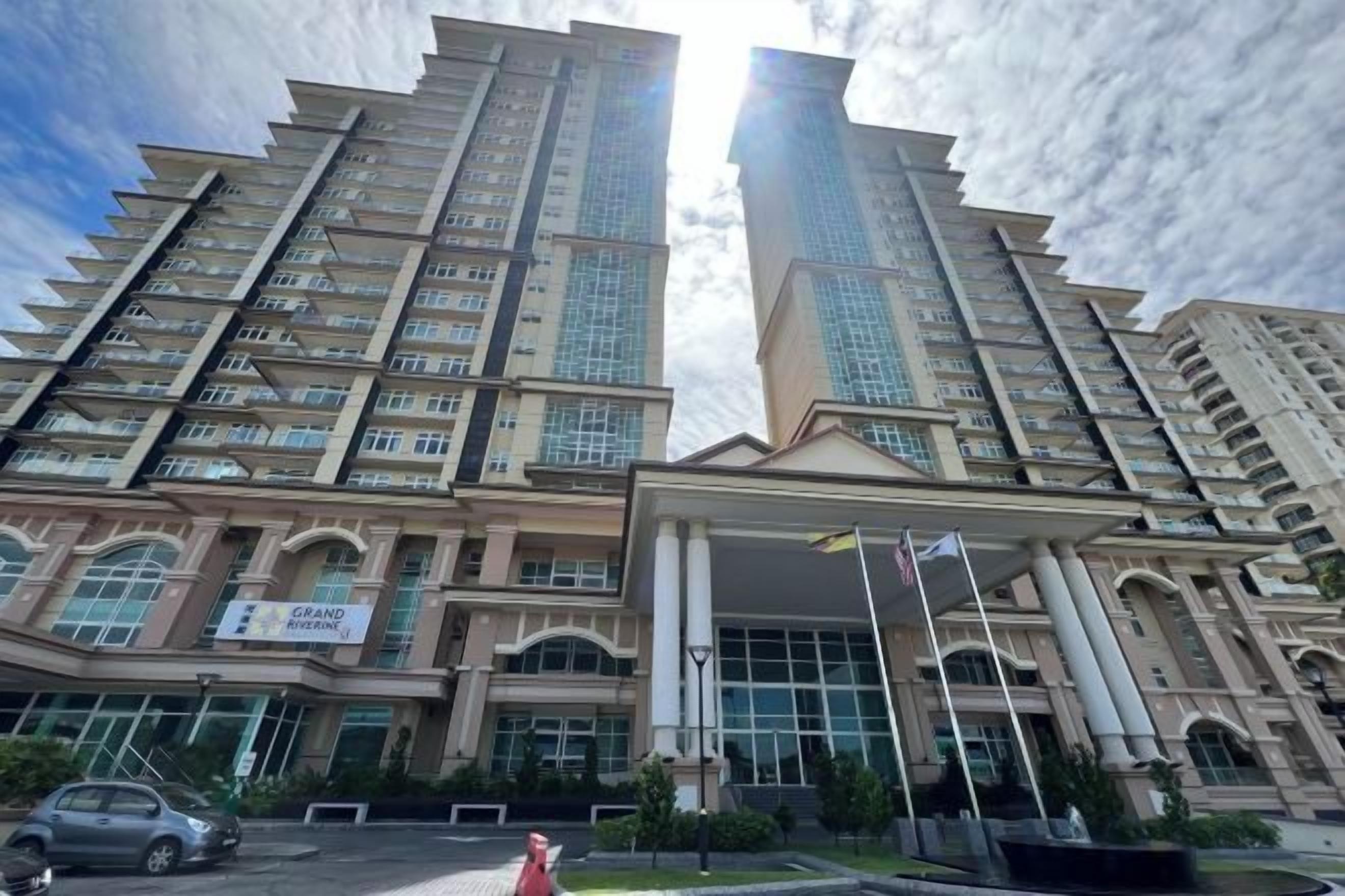 A high-rise building with multiple floors, large windows, and a prominent entrance with a covered area.