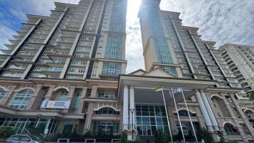 A high-rise building with multiple floors, large windows, and a prominent entrance with a covered area.