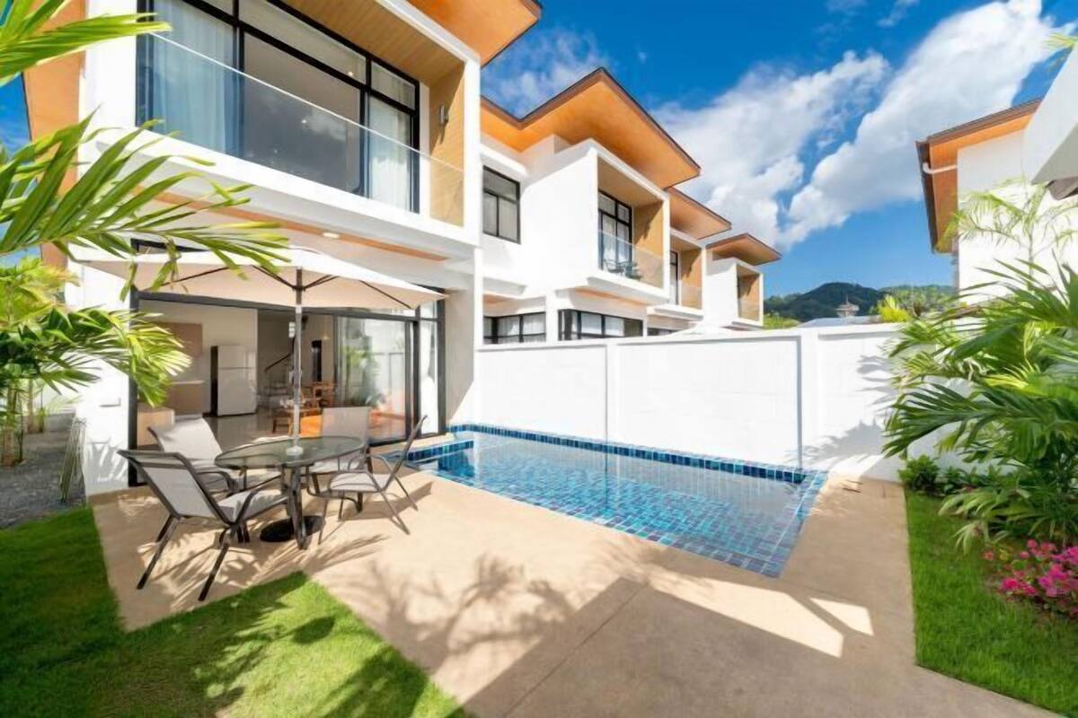 Een modern huis met een zwembad, terras en weelderige beplanting.