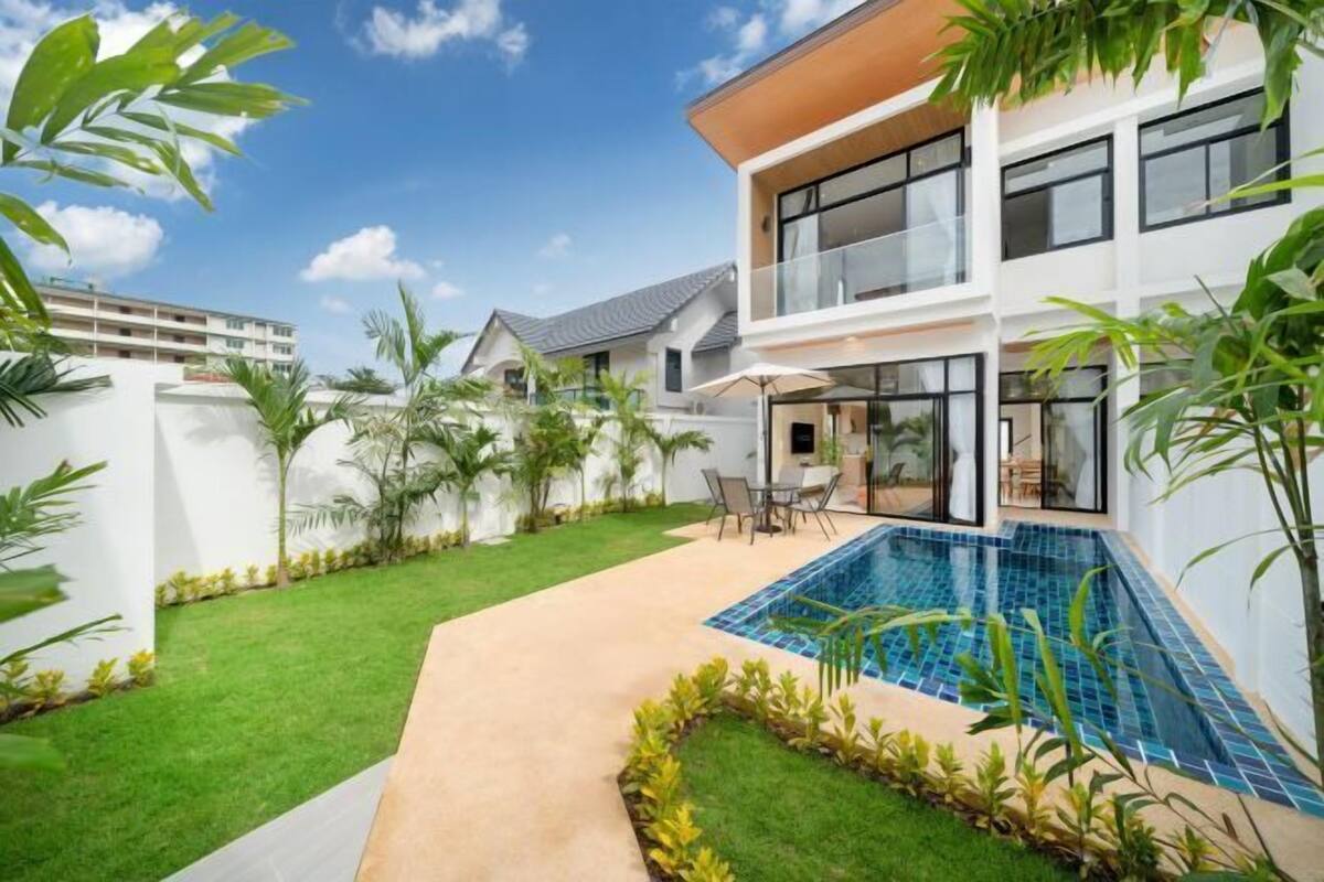 Een modern herenhuis met zwembad, een verzorgd gazon en een patio.
