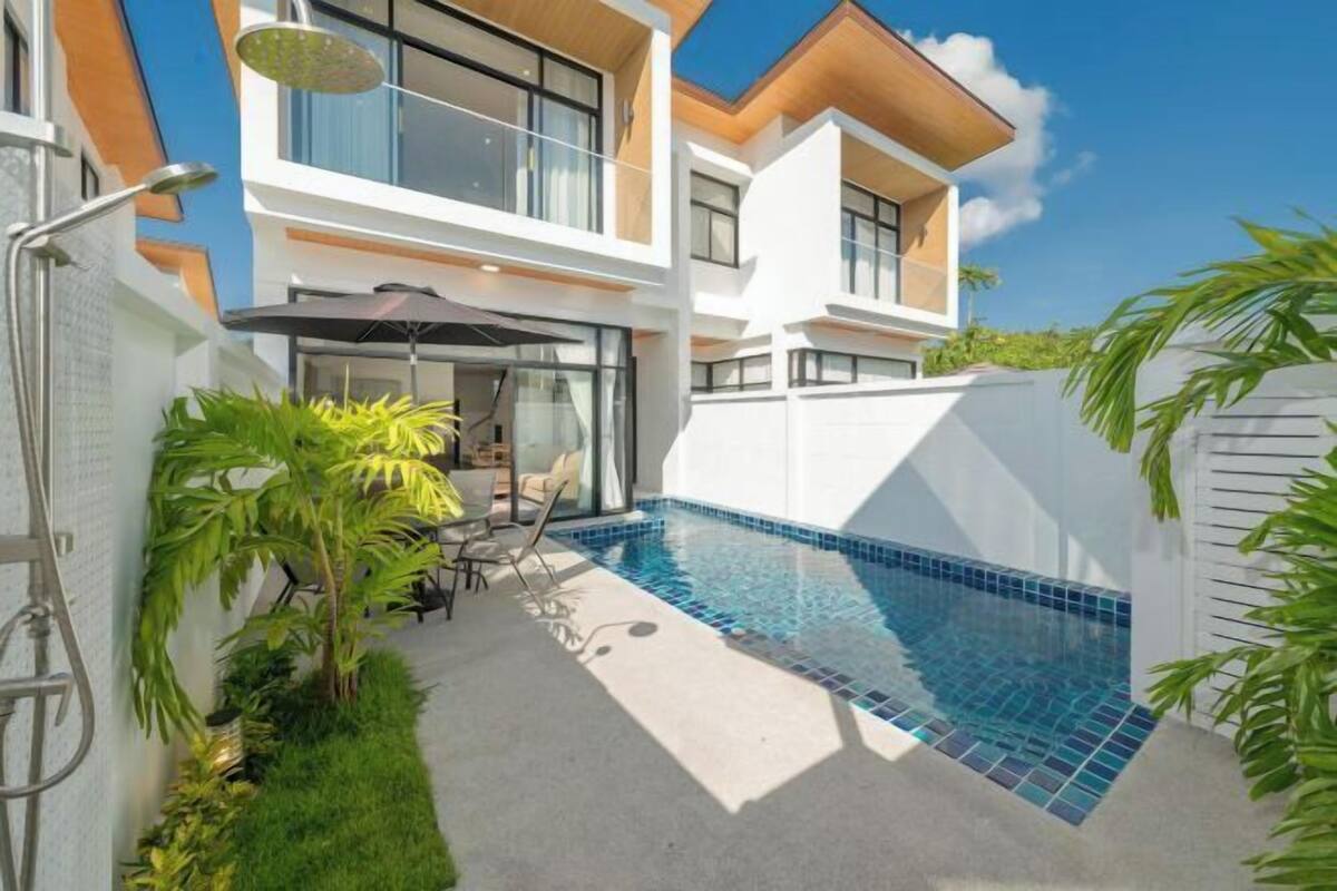 Een modern huis met twee verdiepingen, een zwembad, buitenmeubilair en een overdekt terras.