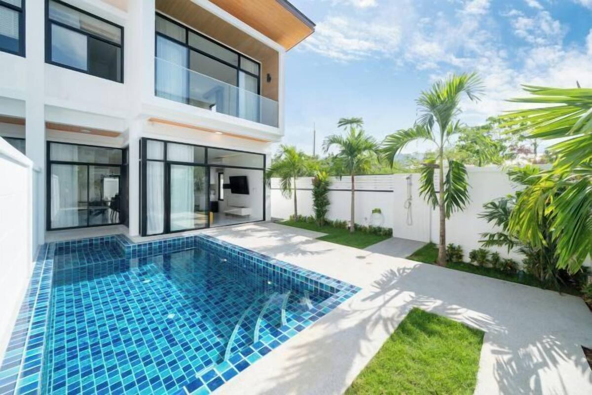 Een modern herenhuis met twee verdiepingen, een zwembad, een balkon en een goed onderhouden tuin.
