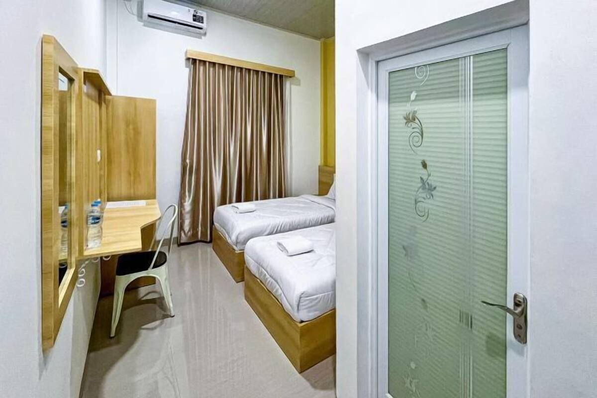 A hotel room with two beds, a desk, a chair, and a wardrobe.
