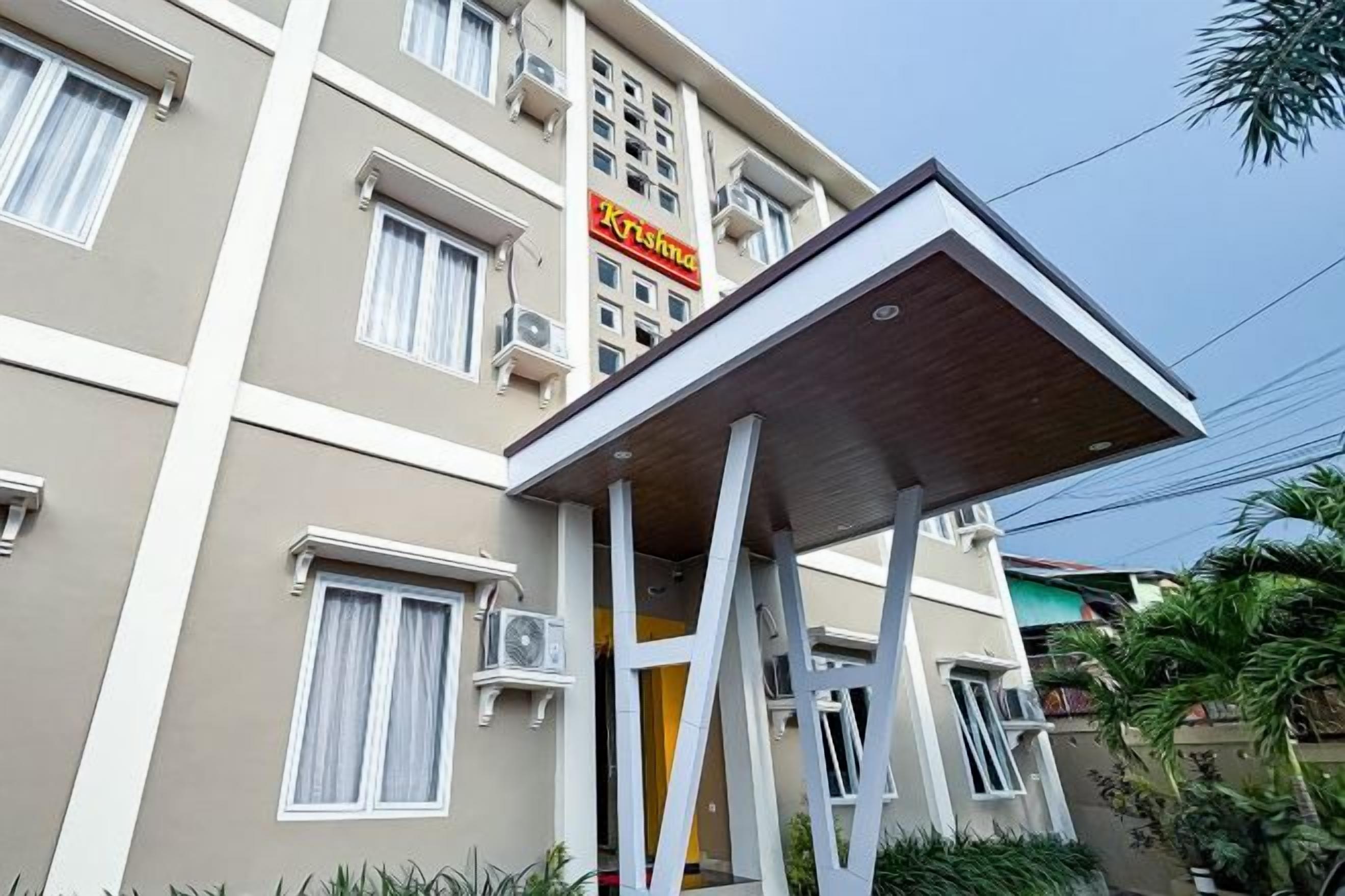 A multi-story hotel with a flat facade, air conditioning units, and a sign indicating the name.