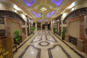 A hotel lobby with a marble floor, a chandelier, and potted plants. - The Muse Pyramids INN (Kafr Nassar)