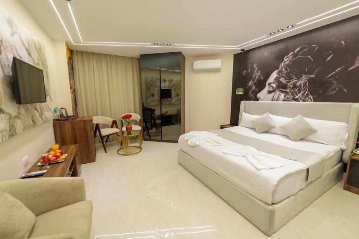 A hotel room with a bed, a desk, a chair, a TV, and a bathroom.