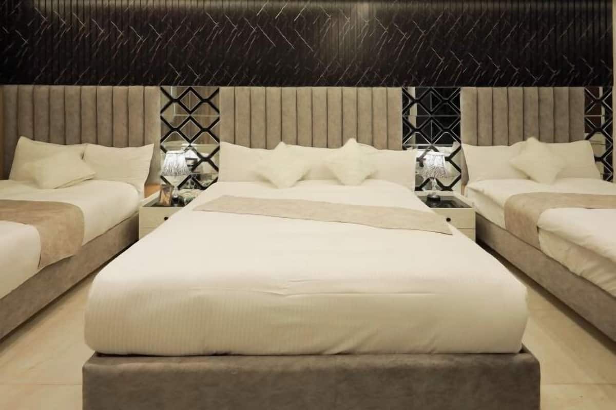 Habitació d'hotel amb un llit gran, dues taules de nit i un capçal de llit amb un disseny geomètric.