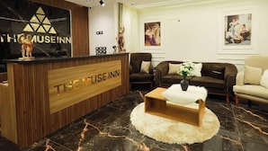 A reception area with a wooden reception desk, a black marble floor, and a sofa set. - The Muse Pyramids INN (Kafr Nassar)