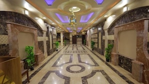 A hotel lobby with a marble floor, a central chandelier, and potted plants. - The Muse Pyramids INN (Kafr Nassar)